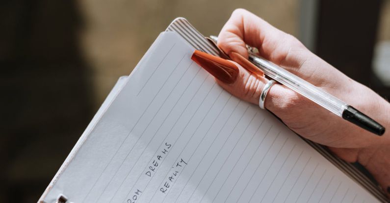 Task Lists - From above of crop anonymous female writing information with pen in notebook on blurred background