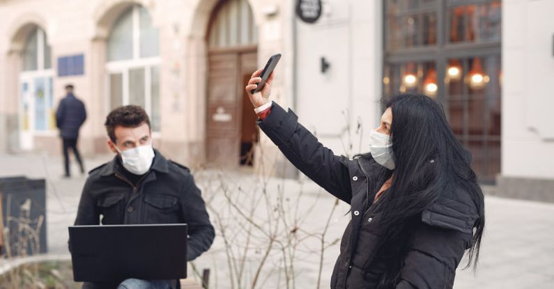 Project Risks - Young couple wearing medical masks using laptop and smartphone on city street